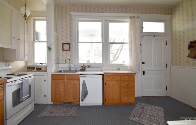 kitchen featuring white appliances, a sink, light countertops, brown cabinetry, and wallpapered walls