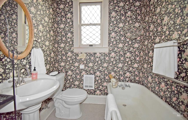 bathroom with a bathtub, wallpapered walls, toilet, a sink, and tile patterned floors