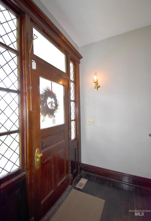 foyer entrance with visible vents, baseboards, and wood finished floors