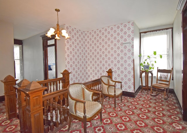 living area featuring a chandelier, an accent wall, an upstairs landing, baseboards, and wallpapered walls