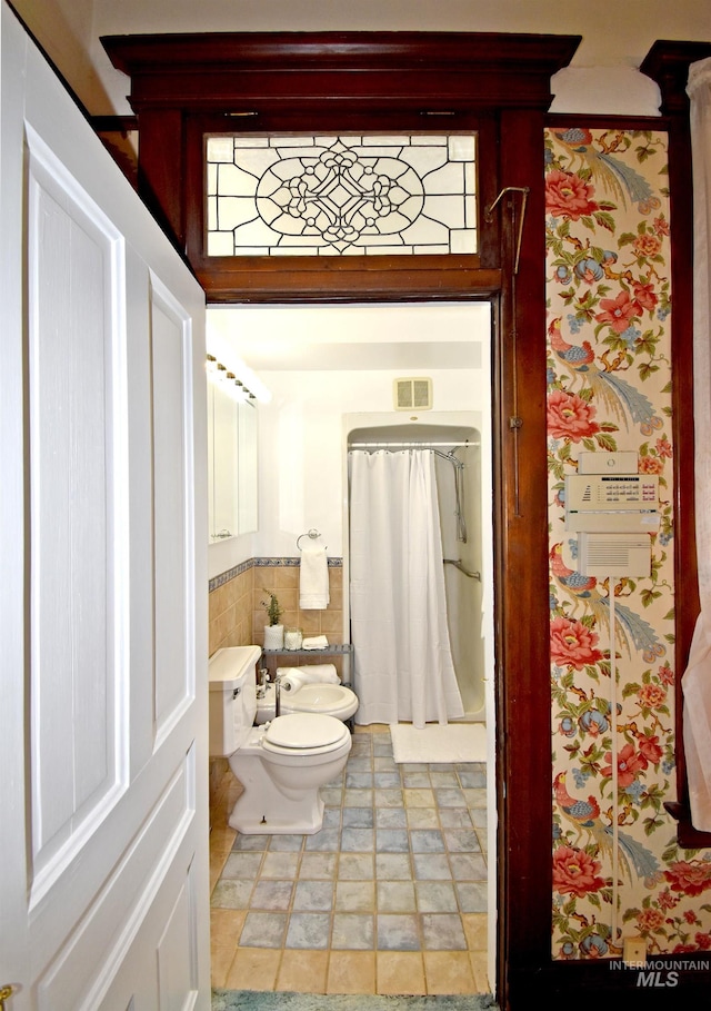 full bathroom featuring tile walls, visible vents, toilet, a stall shower, and a bidet