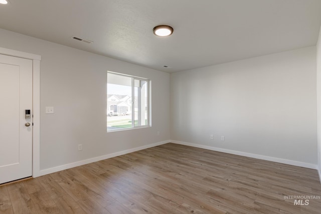 spare room with baseboards, visible vents, and wood finished floors