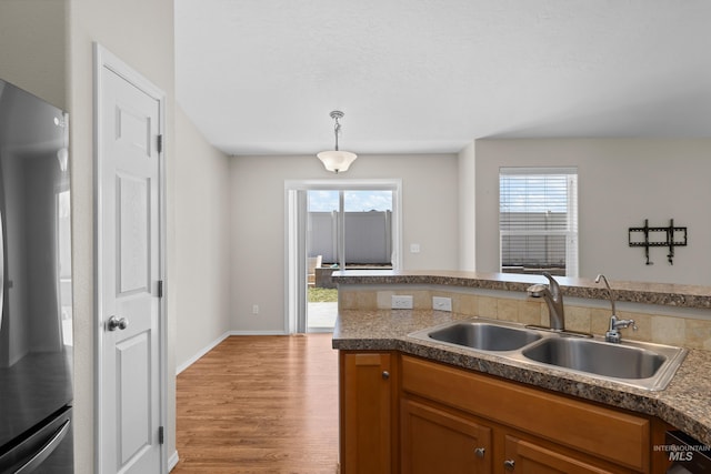 kitchen with plenty of natural light, wood finished floors, freestanding refrigerator, and a sink