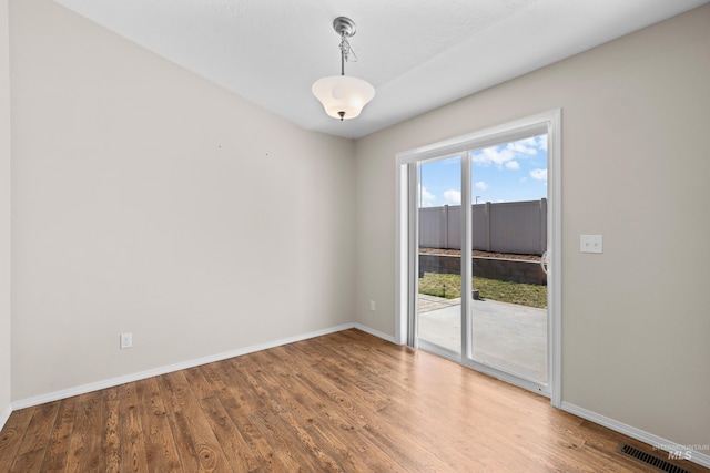 empty room with visible vents, baseboards, and wood finished floors