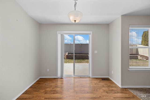 spare room with wood finished floors, baseboards, and a wealth of natural light