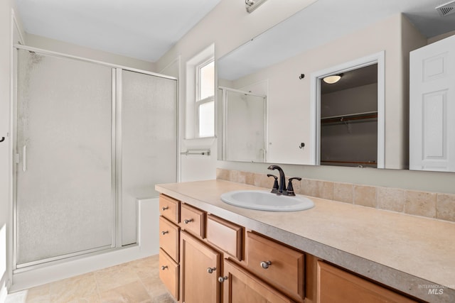 bathroom featuring tile patterned flooring, visible vents, a stall shower, and vanity