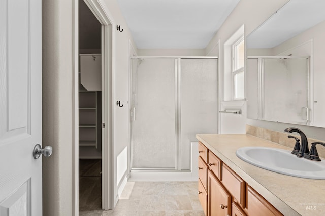 full bath featuring vanity, a spacious closet, and a shower stall