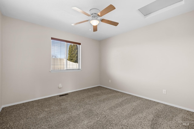 empty room with visible vents, baseboards, ceiling fan, carpet, and attic access