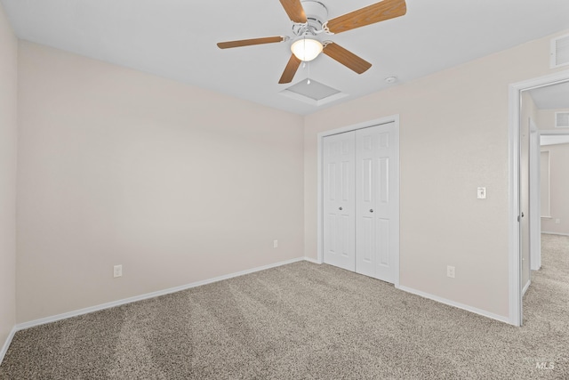 unfurnished bedroom featuring a closet, baseboards, carpet, and attic access