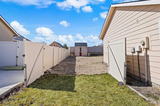 view of yard featuring a storage unit, an outdoor structure, a fenced backyard, and a gate