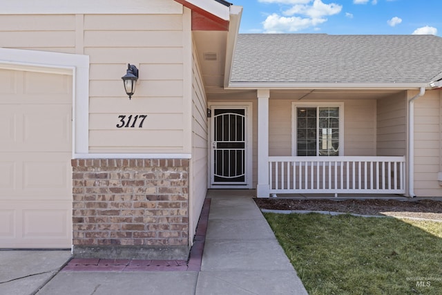 doorway to property with a porch, an attached garage, and a shingled roof