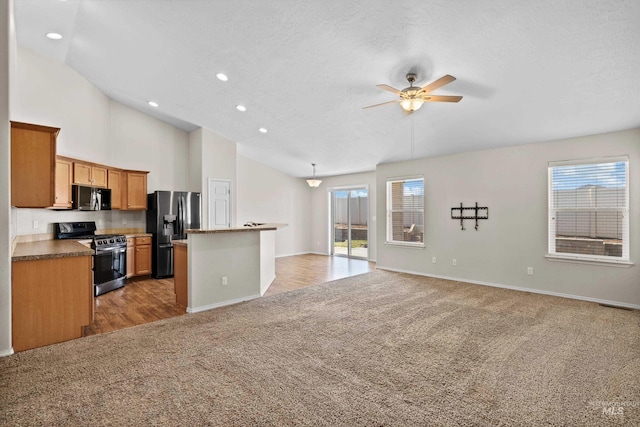 kitchen with ceiling fan, stainless steel appliances, light carpet, open floor plan, and a center island