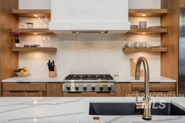 kitchen with brown cabinetry, custom exhaust hood, open shelves, and decorative backsplash