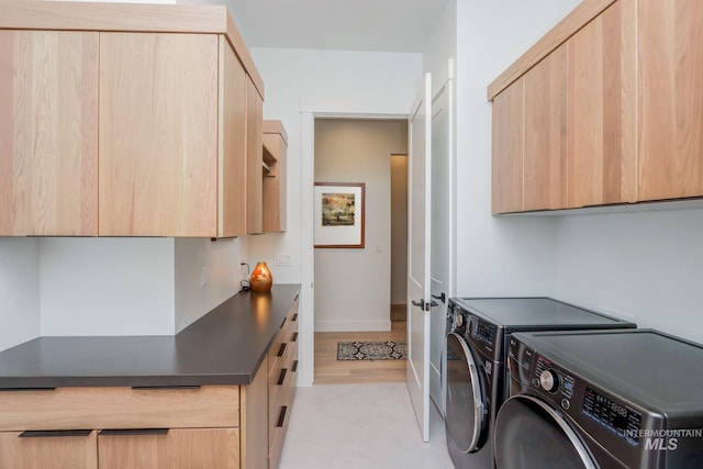 laundry room featuring cabinet space, baseboards, light wood-style floors, and washer and dryer