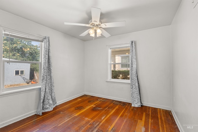 spare room featuring a wealth of natural light, dark wood-type flooring, and ceiling fan