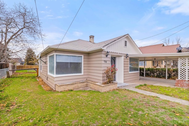 back of house featuring a lawn and a carport