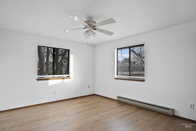 empty room featuring baseboard heating, baseboards, ceiling fan, and wood finished floors