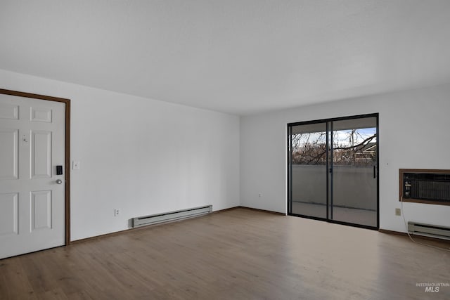 empty room featuring wood finished floors, a wall mounted air conditioner, baseboards, and a baseboard radiator