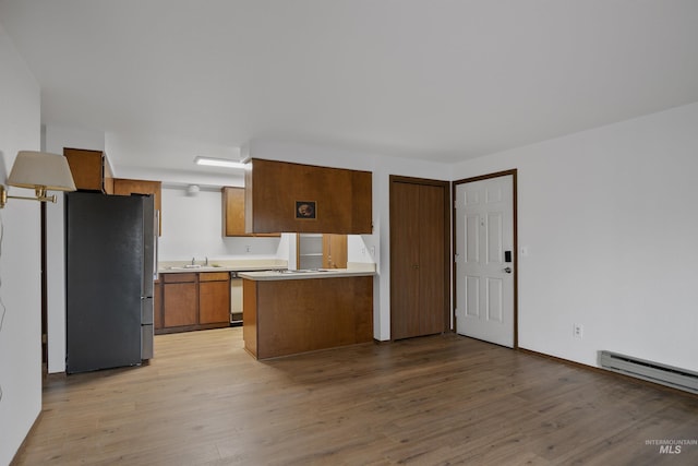 kitchen featuring brown cabinets, light wood-style flooring, light countertops, and freestanding refrigerator