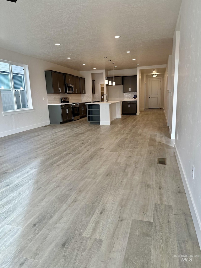 unfurnished living room with a textured ceiling, light hardwood / wood-style floors, and sink