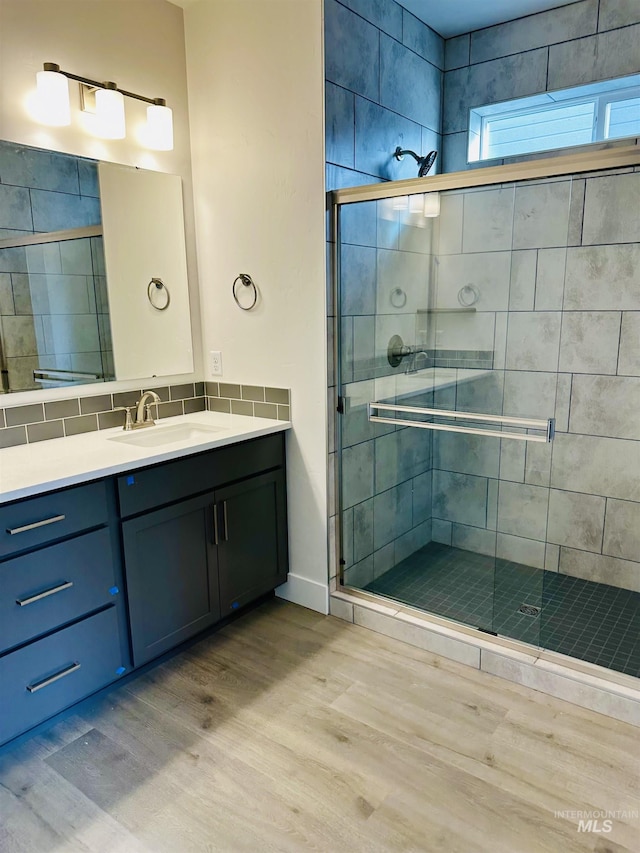 bathroom with wood-type flooring, vanity, and a shower with shower door