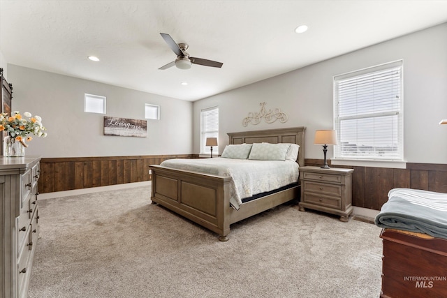 bedroom featuring wainscoting, wood walls, and light carpet