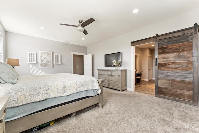 bedroom featuring recessed lighting, light colored carpet, ceiling fan, and a barn door