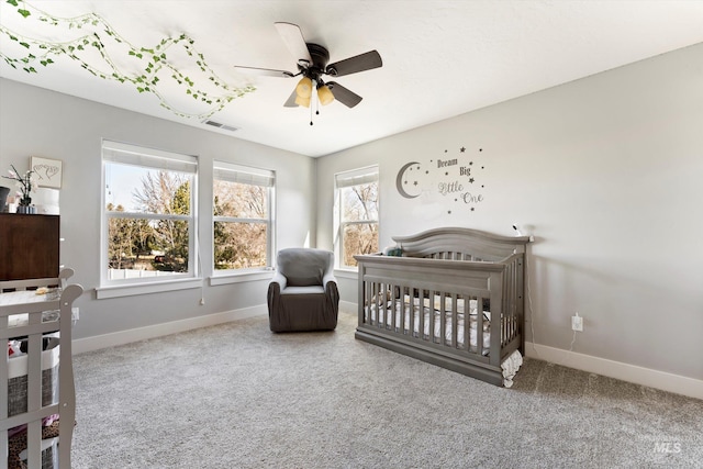 bedroom featuring visible vents, carpet flooring, ceiling fan, a crib, and baseboards