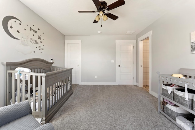 bedroom with carpet, visible vents, a ceiling fan, a crib, and baseboards