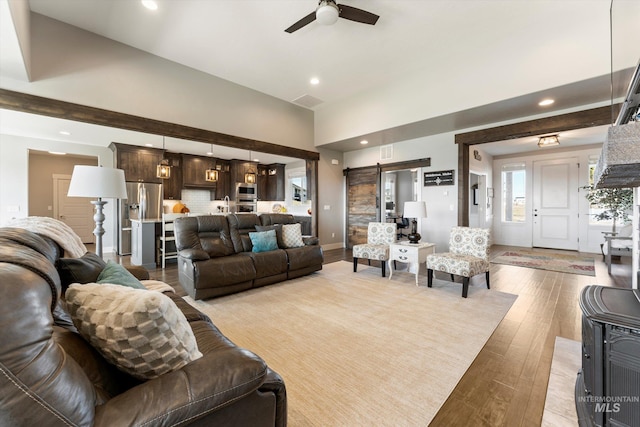 living room with a barn door, recessed lighting, a high ceiling, a ceiling fan, and light wood-type flooring