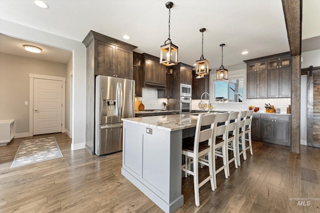 kitchen with stainless steel appliances, a sink, light wood-style flooring, and dark brown cabinets