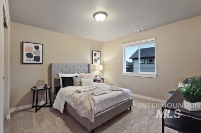 bedroom with light colored carpet and a textured ceiling