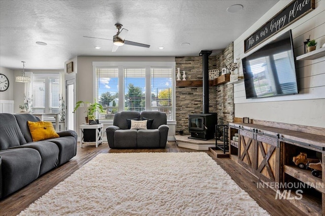 27985 Gray Sage Rd, Caldwell, ID 83607 - living room with a wood stove, ceiling fan, a textured ceiling, and wood finished floors