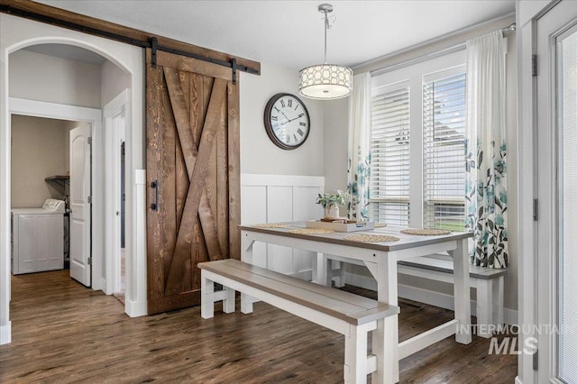 27985 Gray Sage Rd, Caldwell, ID 83607 - dining space with separate washer and dryer, a barn door, wood finished floors, wainscoting, and arched walkways