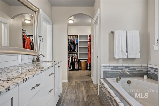 27985 Gray Sage Rd, Caldwell, ID 83607 - bathroom with vanity, a walk in closet, a garden tub, backsplash, and baseboards