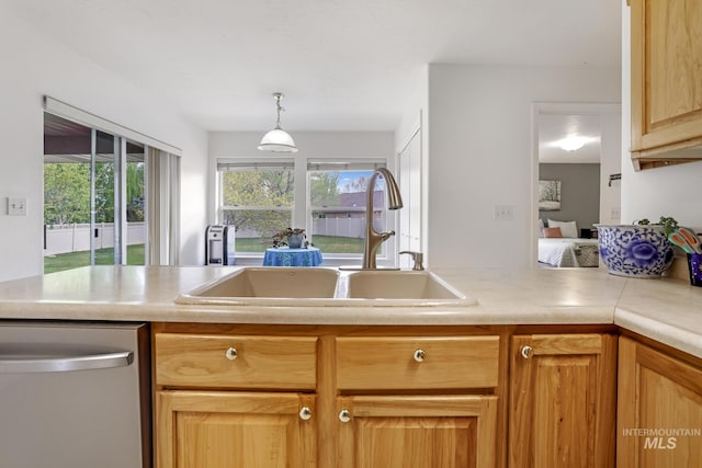 kitchen featuring stainless steel dishwasher, a sink, pendant lighting, and light countertops