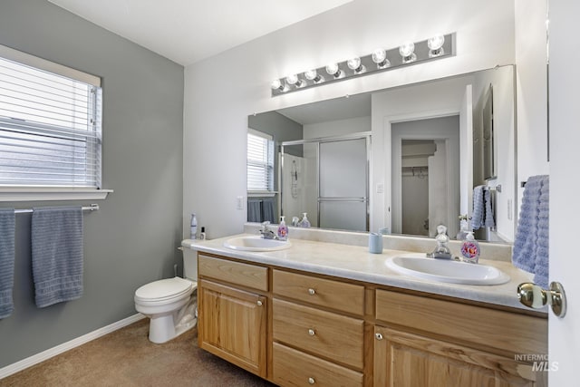 bathroom with double vanity, baseboards, a sink, and a stall shower