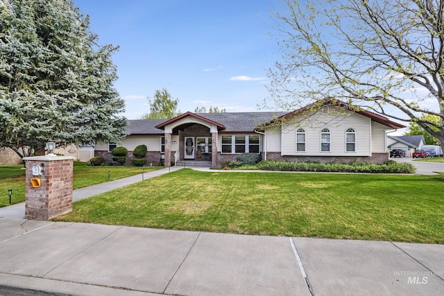 single story home with brick siding, a shingled roof, and a front lawn