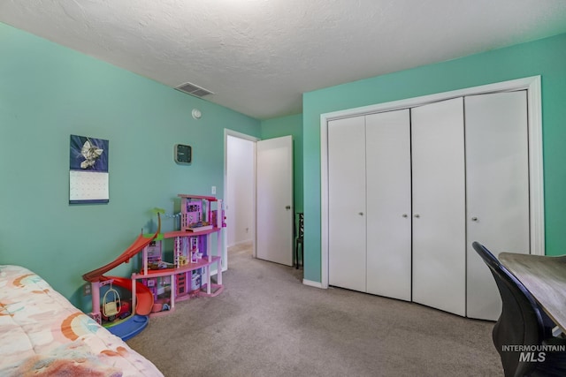 bedroom featuring a textured ceiling, visible vents, carpet, and a closet