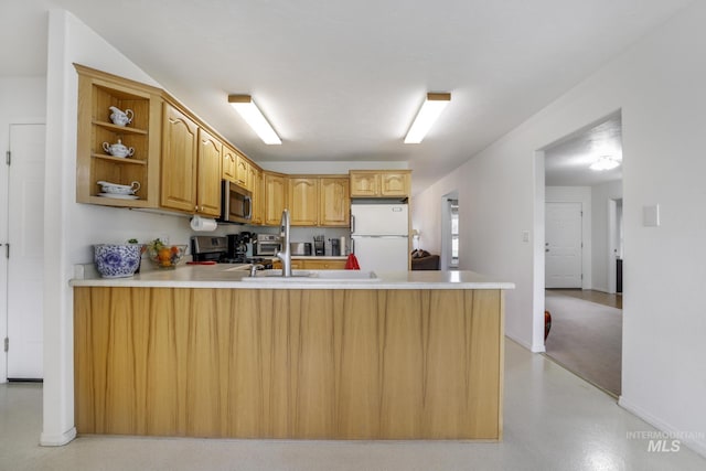 kitchen featuring open shelves, light countertops, freestanding refrigerator, stainless steel microwave, and a peninsula