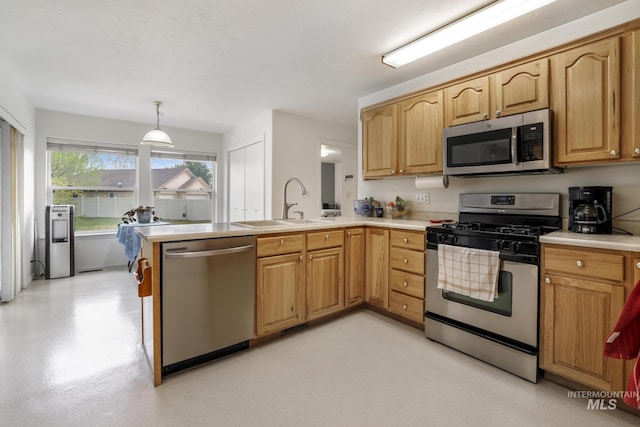 kitchen featuring light countertops, a sink, a peninsula, and stainless steel appliances