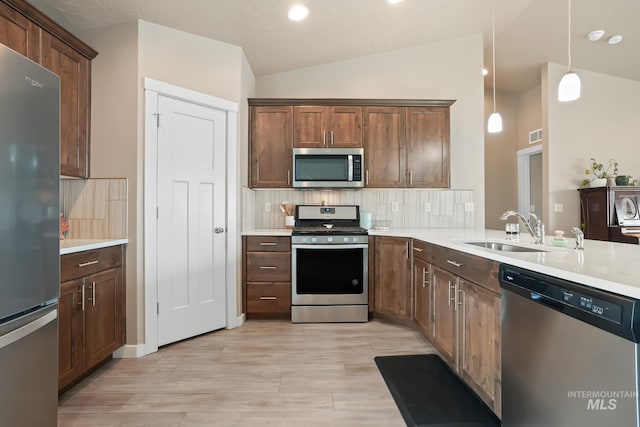 319 Magnolia Ave, Fruitland, ID 83619 - kitchen with stainless steel appliances, a sink, lofted ceiling, decorative backsplash, and light wood finished floors