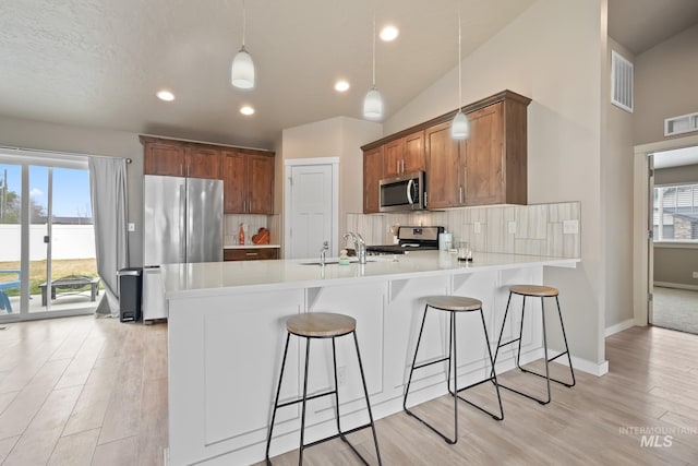 319 Magnolia Ave, Fruitland, ID 83619 - kitchen with appliances with stainless steel finishes, a peninsula, a sink, backsplash, and light wood finished floors