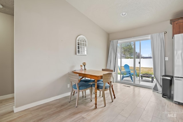 319 Magnolia Ave, Fruitland, ID 83619 - dining room featuring light wood-style flooring, a textured ceiling, baseboards, and lofted ceiling
