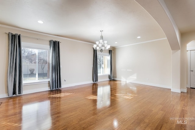 unfurnished room with baseboards, arched walkways, ornamental molding, and light wood finished floors