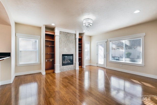 unfurnished living room with recessed lighting, wood finished floors, baseboards, and a large fireplace