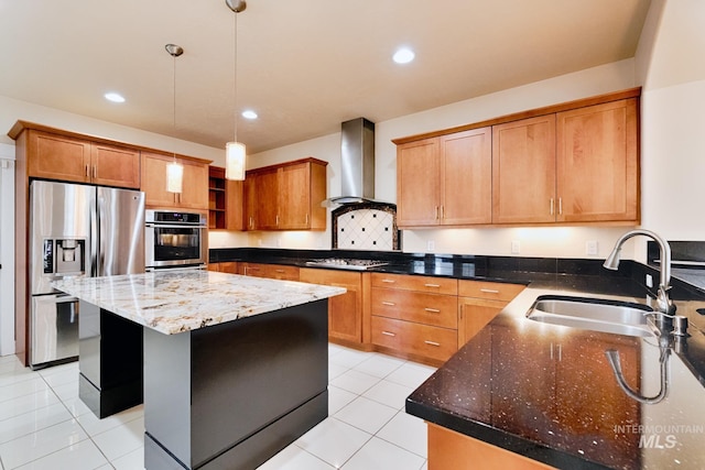 kitchen with a center island, dark stone counters, stainless steel appliances, wall chimney exhaust hood, and a sink