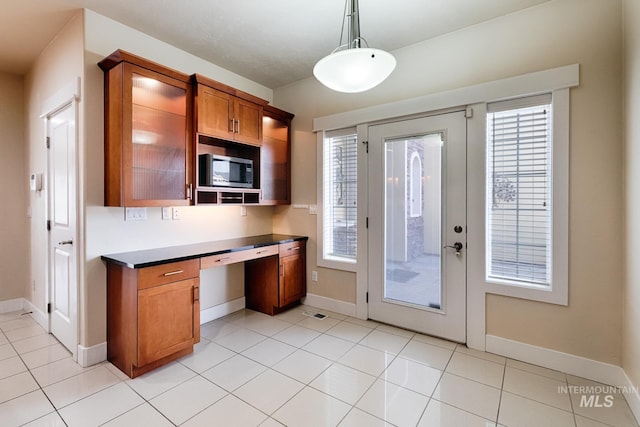 kitchen with dark countertops, stainless steel microwave, brown cabinets, and a healthy amount of sunlight