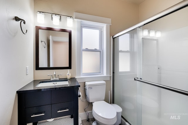 bathroom featuring toilet, a stall shower, and vanity