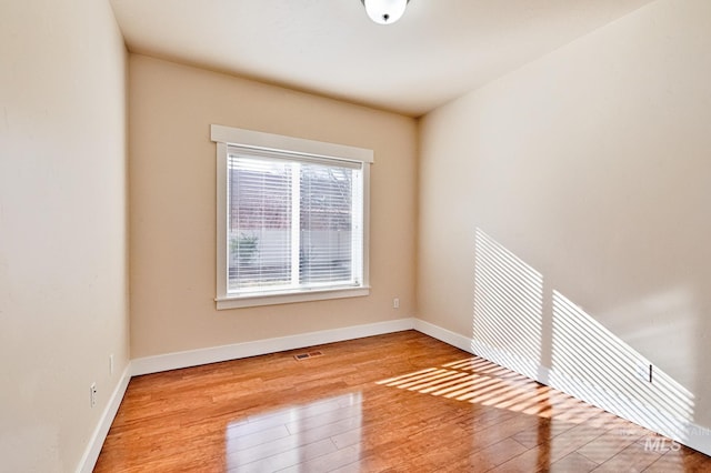 spare room featuring baseboards, visible vents, and wood-type flooring